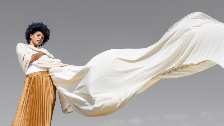 Curly Haired Woman with flowing white fabric against a gray background